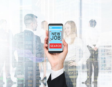 A hand holds a smartphone with the text "new job search" on the screen. A business couple in blur is on the background.