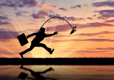 Silhouette of businessman running for the carrot and reflection in water. Concept of money and business